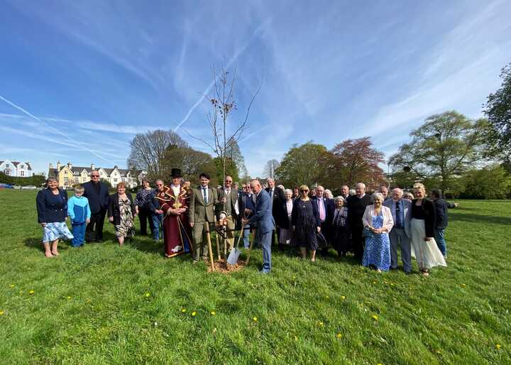A large group of people standing on grass under a blue sky.