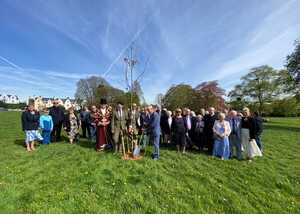 A large group of people standing on grass under a blue sky.